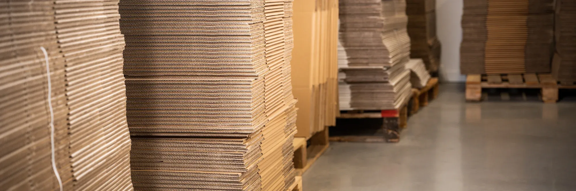 Stapels vlakke kartonnen dozen in het magazijn